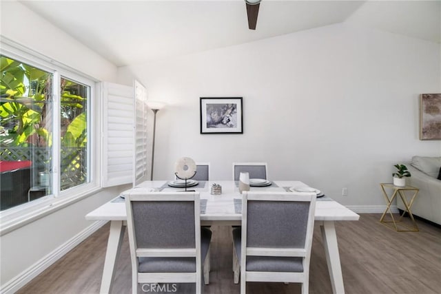 dining space with lofted ceiling, baseboards, and wood finished floors