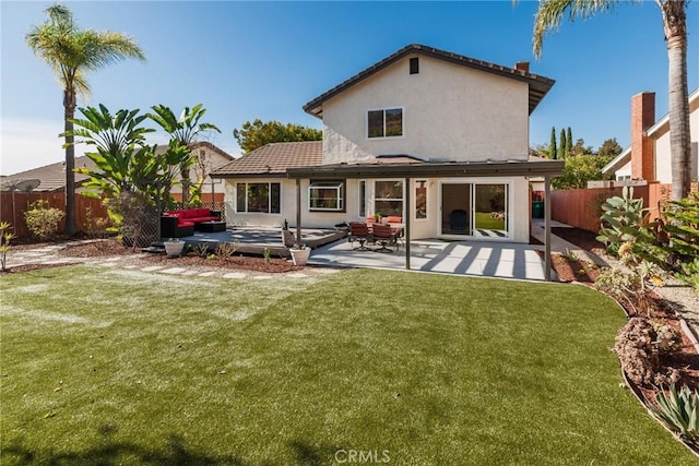 back of house with a fenced backyard, a patio, a lawn, and stucco siding