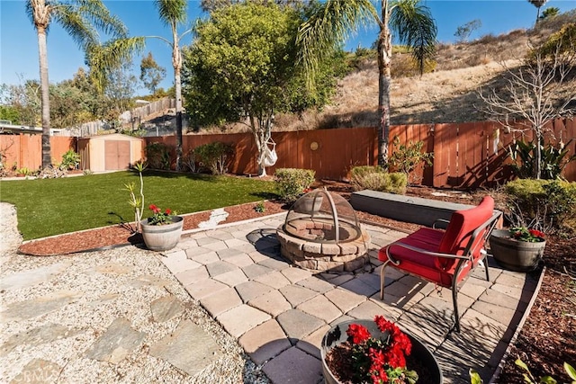 view of patio / terrace with a fire pit, a storage unit, an outdoor structure, and a fenced backyard