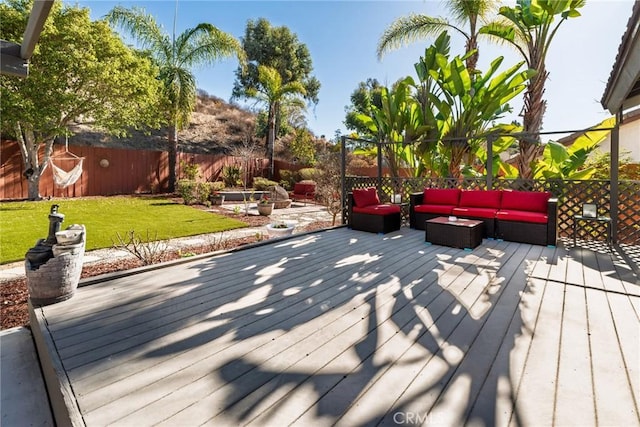 deck featuring a fenced backyard, outdoor lounge area, and a lawn