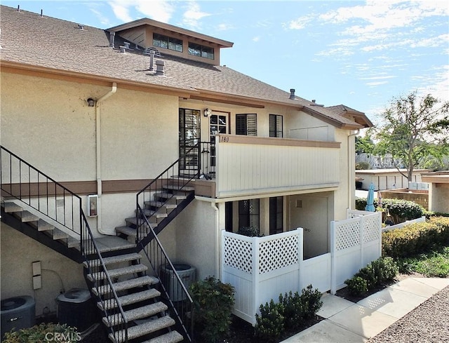 view of front of property with stairs, central AC, and roof with shingles