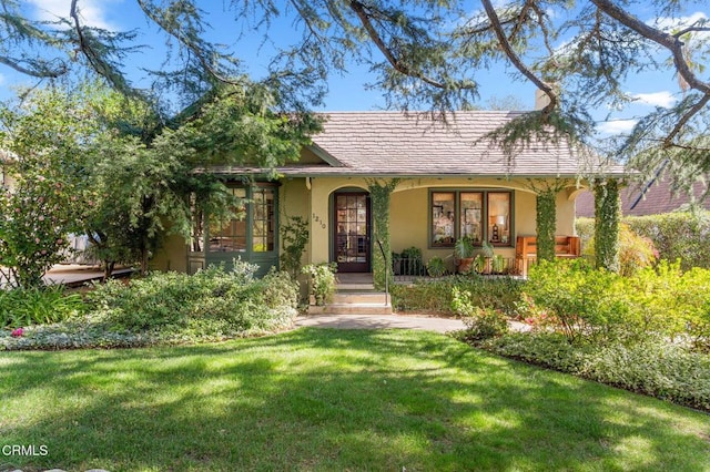 view of front of home with a porch, a front lawn, and stucco siding