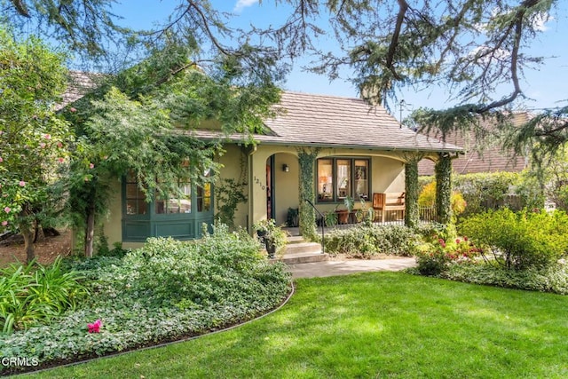 view of front of home featuring covered porch, stucco siding, and a front yard