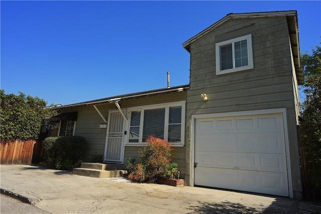 view of front of house featuring driveway, a garage, and fence