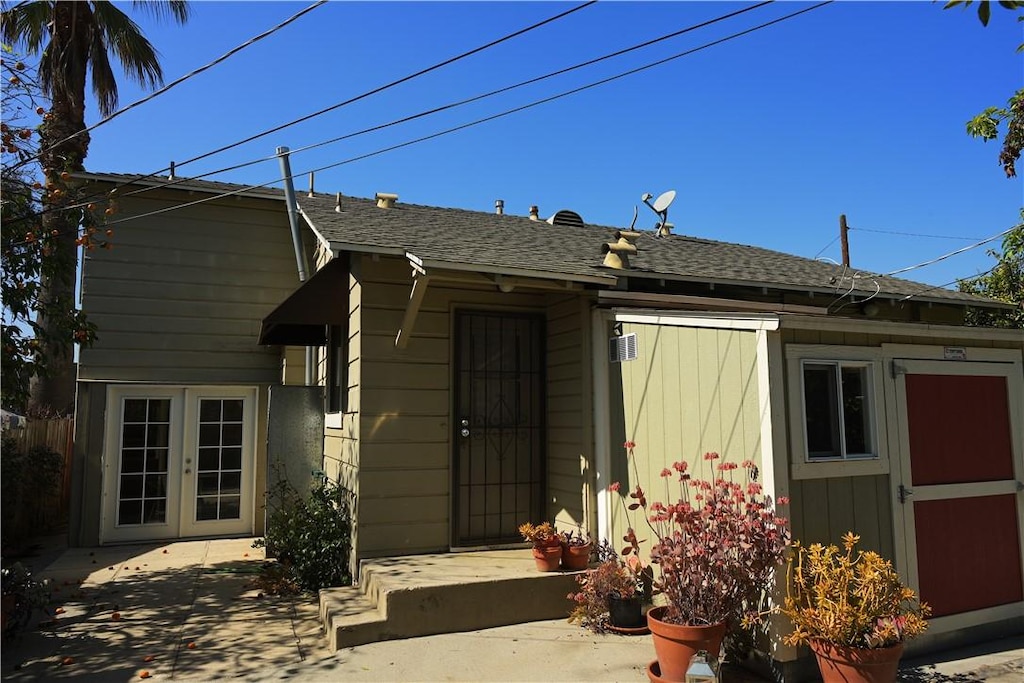 view of front of home featuring french doors and roof with shingles