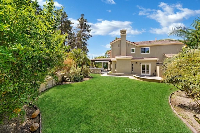 rear view of house featuring a patio area, a yard, and a chimney