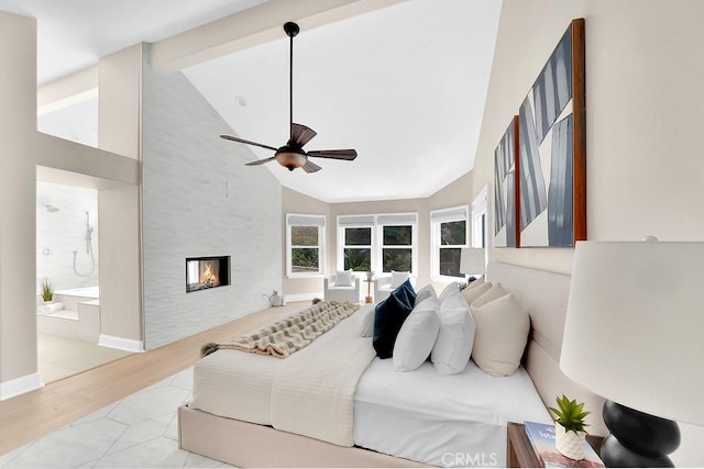 bedroom with a fireplace, ensuite bathroom, wood finished floors, high vaulted ceiling, and baseboards