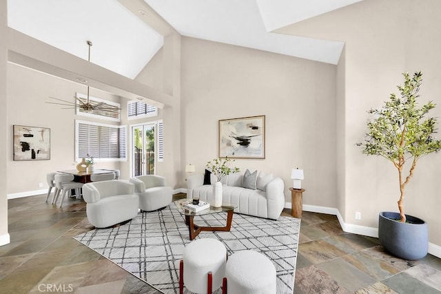 living room with stone finish floor, high vaulted ceiling, baseboards, and a ceiling fan