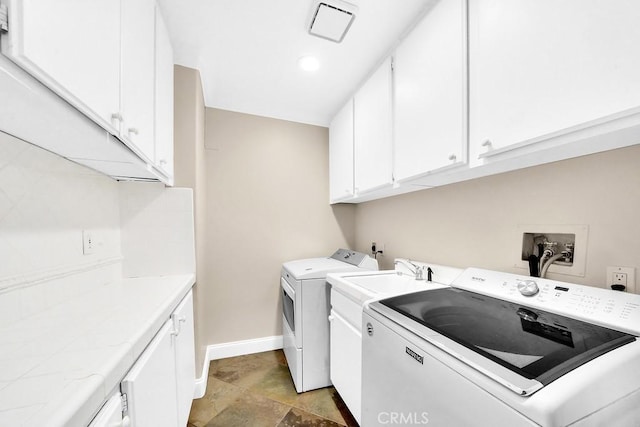 washroom featuring washing machine and clothes dryer, cabinet space, and baseboards