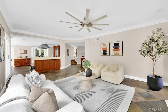 living room with ceiling fan, visible vents, baseboards, stairs, and crown molding