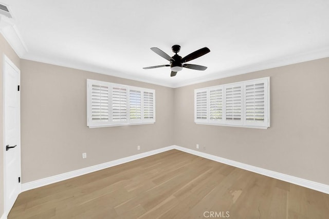 spare room featuring ornamental molding, wood finished floors, a ceiling fan, and baseboards