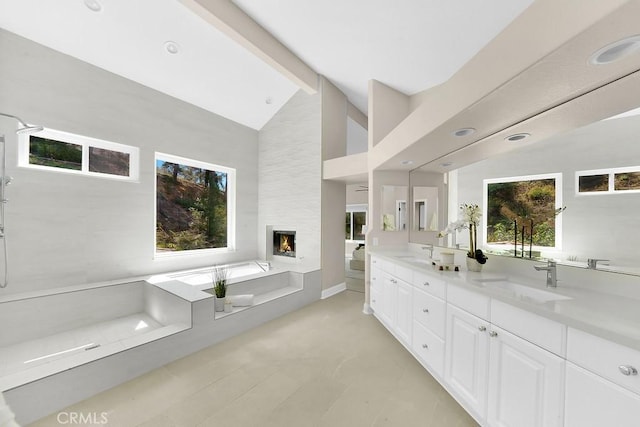 full bathroom with a garden tub, double vanity, a fireplace, and a sink