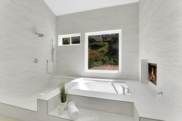 full bathroom featuring a large fireplace and a tile shower