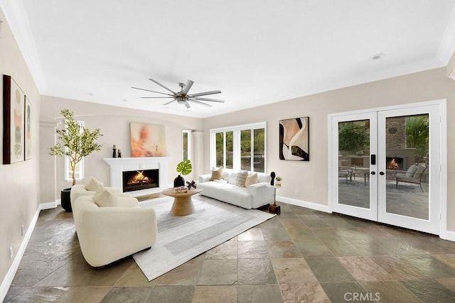 living area with french doors, crown molding, stone tile floors, a warm lit fireplace, and baseboards