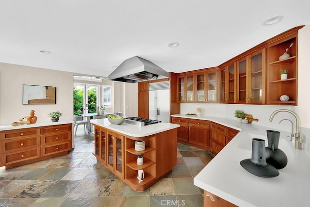 kitchen featuring built in fridge, a center island, open shelves, light countertops, and island range hood