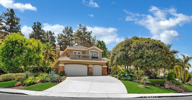 view of front of home featuring concrete driveway, stucco siding, a chimney, an attached garage, and a front yard