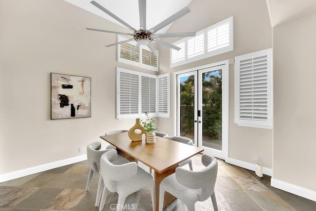 dining space with a ceiling fan, french doors, a towering ceiling, and baseboards