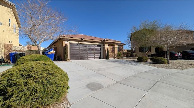 view of front of house featuring concrete driveway, an attached garage, a tiled roof, and stucco siding