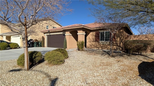 view of front facade featuring a garage, concrete driveway, a tile roof, and stucco siding