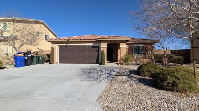 mediterranean / spanish-style house with an attached garage, a tiled roof, concrete driveway, and stucco siding