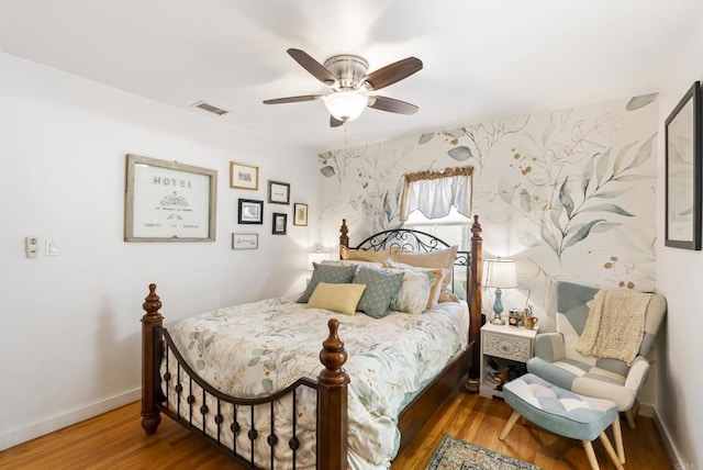 bedroom featuring a ceiling fan, baseboards, visible vents, and wood finished floors