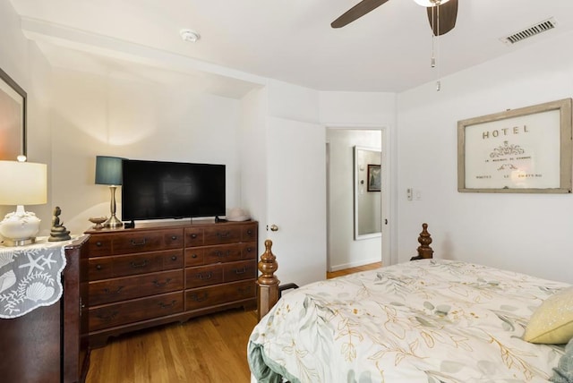 bedroom featuring a ceiling fan, visible vents, and wood finished floors