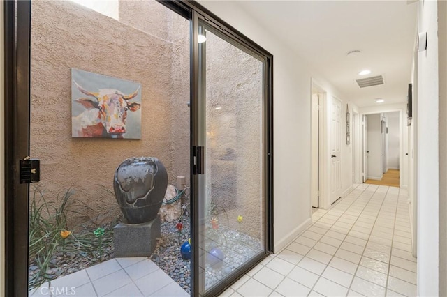 hall featuring tile patterned flooring, visible vents, and baseboards