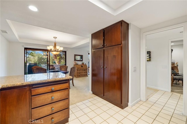 kitchen with visible vents, a tray ceiling, a chandelier, and light tile patterned flooring