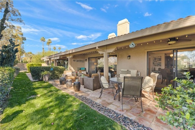 back of house with ceiling fan, a patio, a lawn, stucco siding, and a chimney