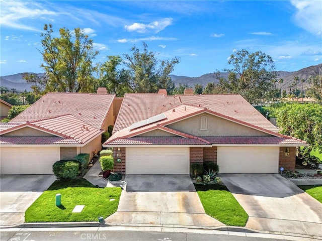 view of front of home featuring driveway, a tile roof, and a mountain view