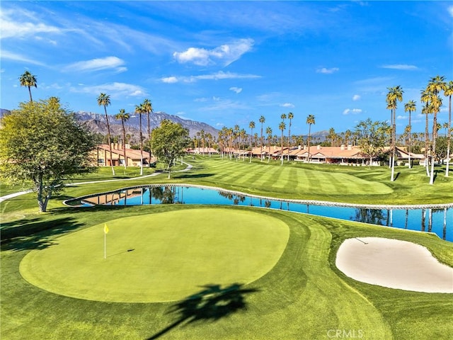 view of community featuring a lawn, golf course view, and a water and mountain view