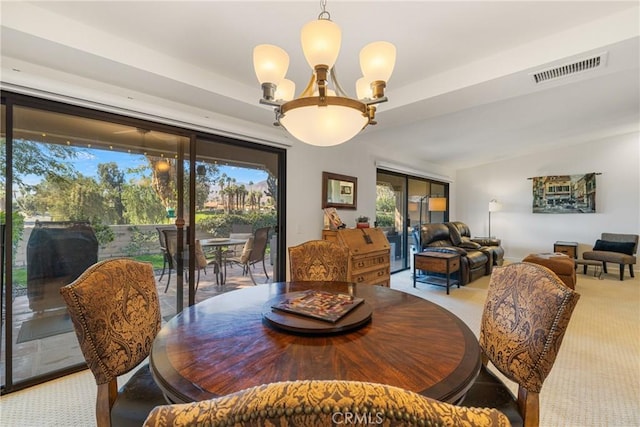 dining space with lofted ceiling, light colored carpet, visible vents, and a notable chandelier