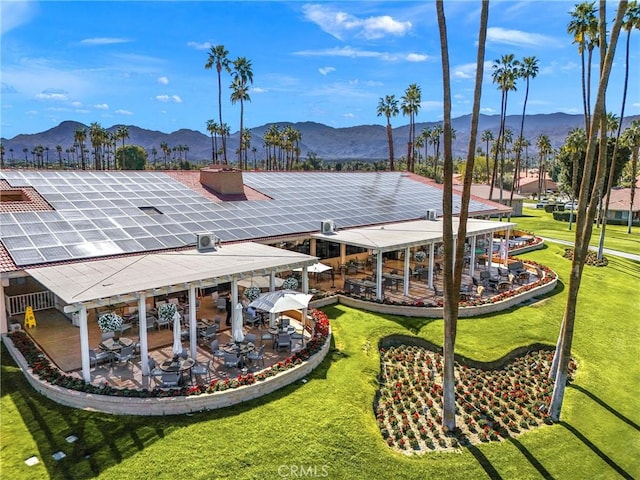 back of house with a patio, a yard, solar panels, and a mountain view