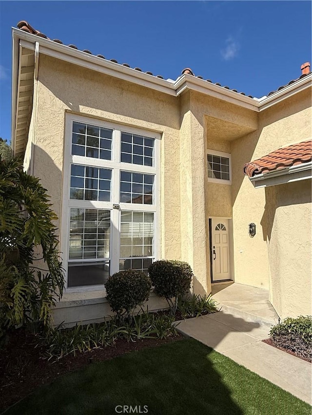 view of exterior entry featuring a tiled roof and stucco siding