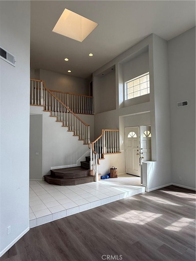 entryway featuring a skylight, visible vents, stairway, and wood finished floors