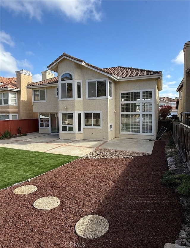 back of house featuring a fenced backyard, a patio, a tiled roof, and stucco siding