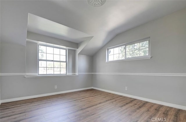 bonus room with a healthy amount of sunlight, vaulted ceiling, and wood finished floors