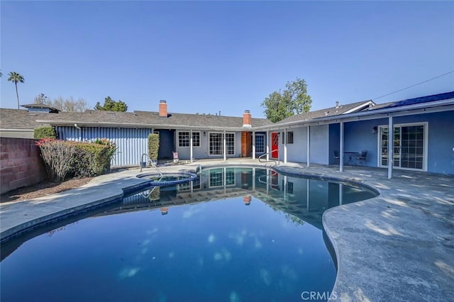 view of pool featuring a patio, fence, and a pool with connected hot tub