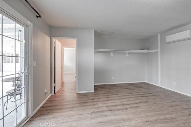 walk in closet featuring light wood finished floors and a wall mounted air conditioner