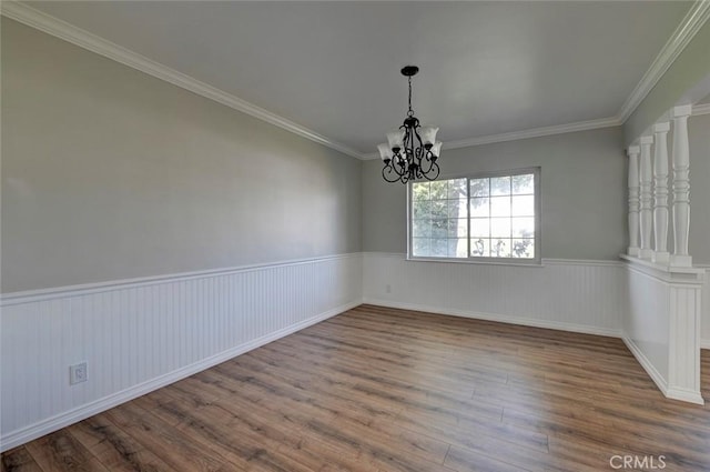 unfurnished room with wainscoting, crown molding, a notable chandelier, and wood finished floors