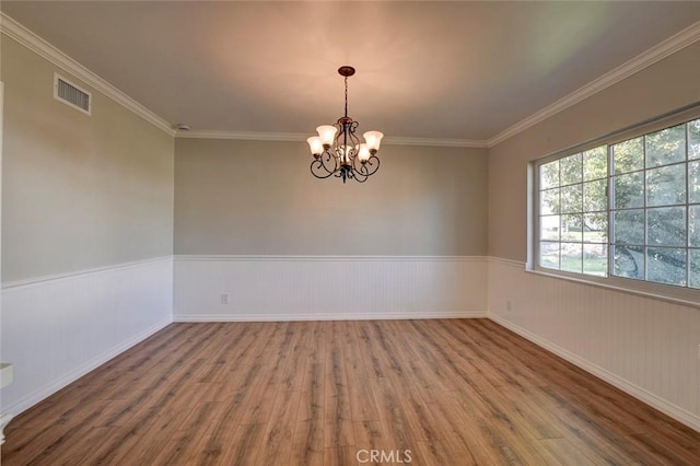 unfurnished room with a chandelier, wainscoting, wood finished floors, and visible vents