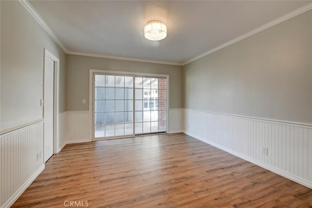 spare room with ornamental molding, a wainscoted wall, and wood finished floors