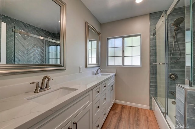 bathroom with double vanity, wood finished floors, a sink, and baseboards