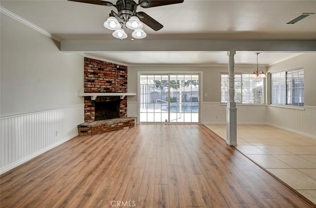 unfurnished living room featuring wainscoting, wood finished floors, and visible vents