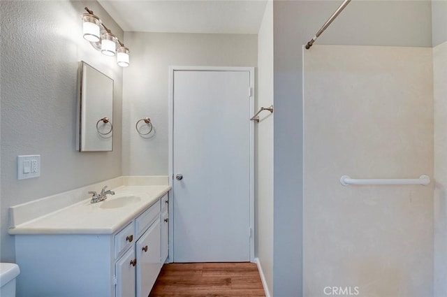 bathroom with toilet, wood finished floors, and vanity