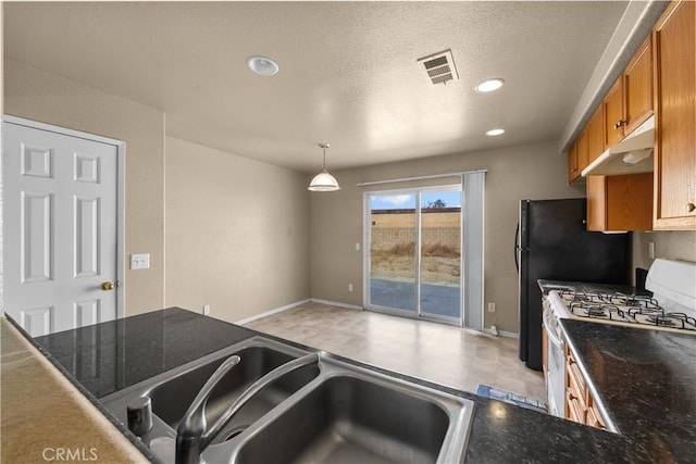 kitchen with under cabinet range hood, a sink, visible vents, brown cabinetry, and gas range