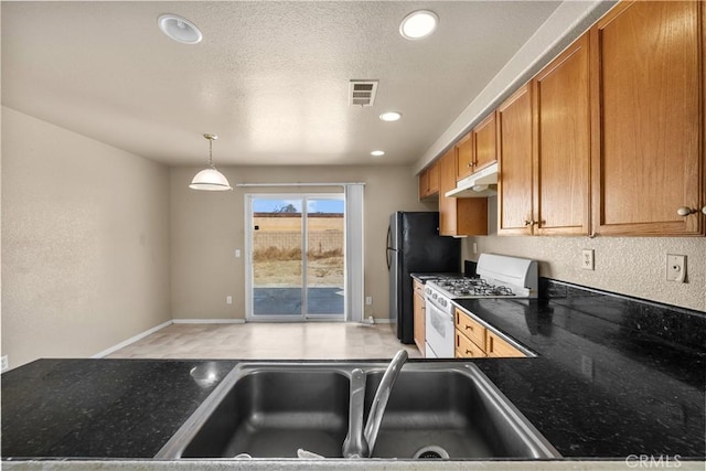 kitchen with visible vents, gas range gas stove, under cabinet range hood, dark countertops, and brown cabinets