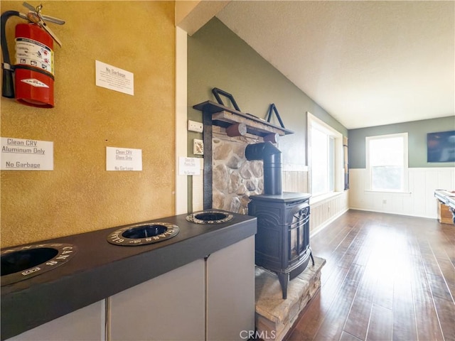 kitchen featuring wainscoting, wood-type flooring, and a wood stove