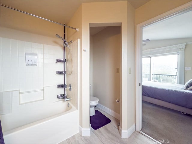 ensuite bathroom featuring toilet, shower / tub combination, baseboards, and connected bathroom