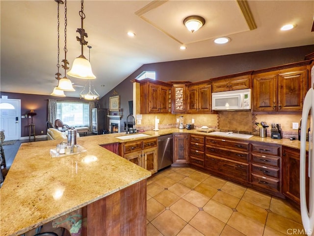 kitchen featuring light stone counters, a peninsula, white appliances, a sink, and backsplash